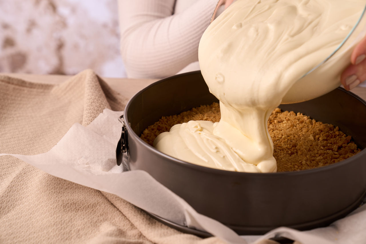 Une main prend un biscuit au chocolat dans un sac à fermeture éclair sur une table en bois avec un tissu jaune.