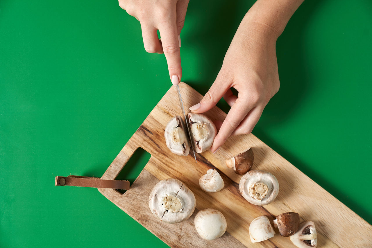 Champignons werden auf einem Schneidebrett in gleichmäßige Stücke geschnitten.
