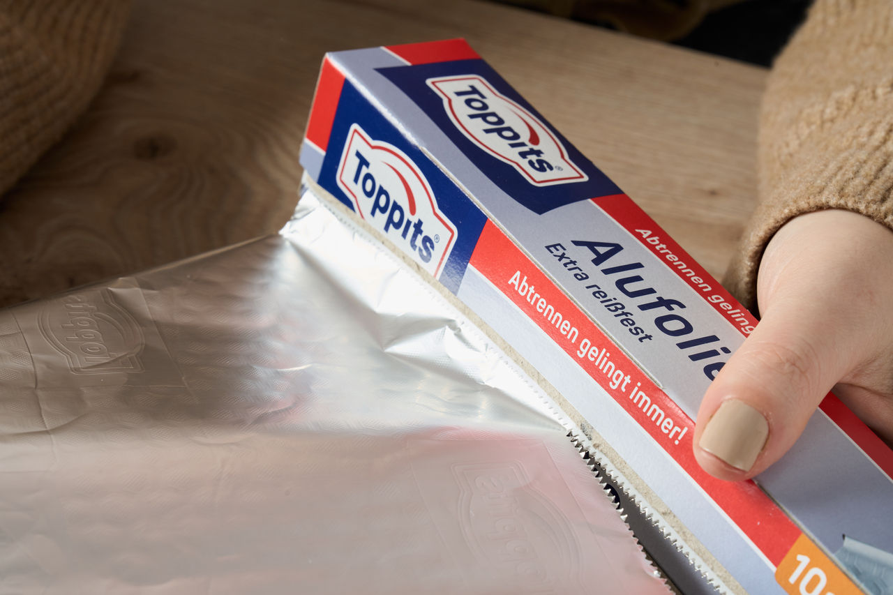 Lachsfilet liegt auf einer Toppits Alufolie in einer schwarzen Backform.