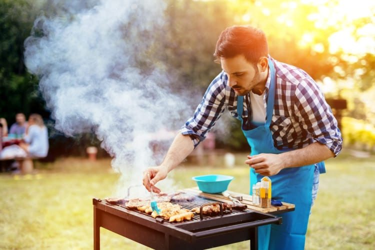 Homme préparant un barbecue au jardin