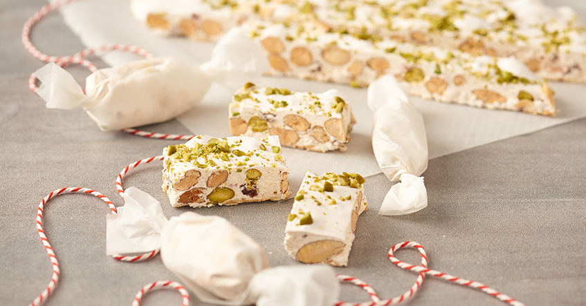 Weißer Nougat oder Turron mit Mandeln und Pistazien auf Backpapier